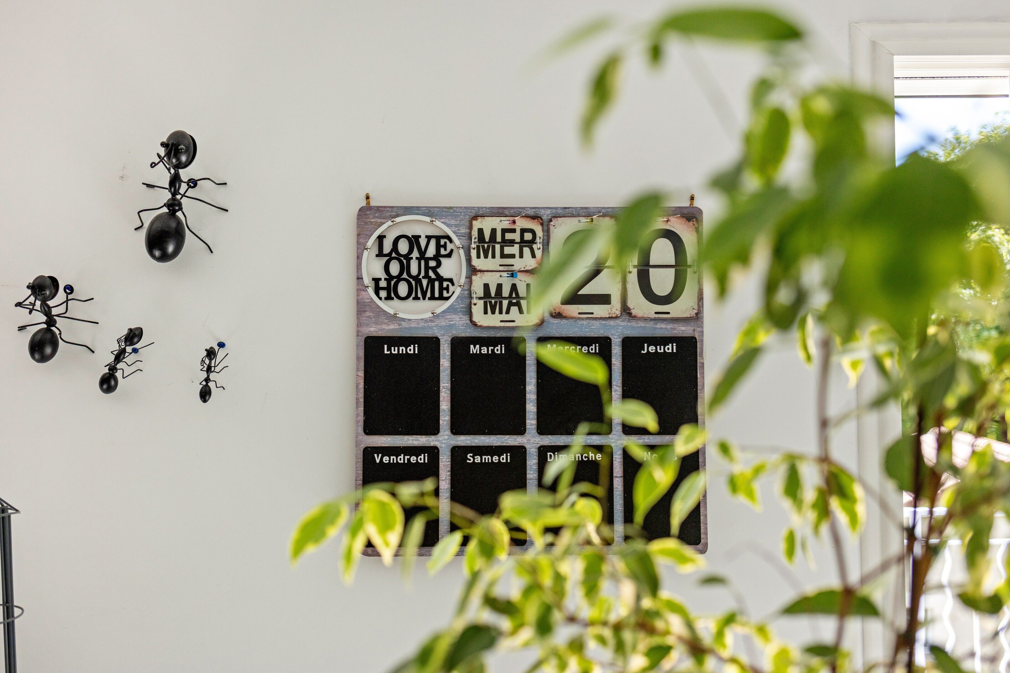 Un mur décoré de petites figurines de fourmis et un calendrier français.