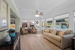 A spacious living room with a large window, a ceiling fan, and a sofa. - A one of a kind oasis, 7 miles from beautiful Annamarie Island IMG academy (Bradenton)