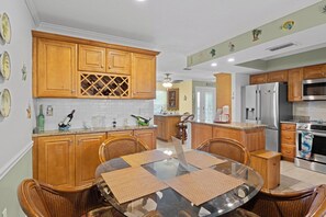 A kitchen with wooden cabinets, a dining table with chairs, and a refrigerator. - A one of a kind oasis, 7 miles from beautiful Annamarie Island IMG academy (Bradenton)