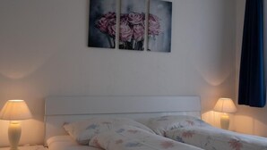 Ein Schlafzimmer mit einem Bett, zwei Nachttischlampen und einem Wandbild mit rosa Blumen.