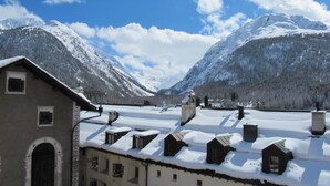 Ein Gebäude mit zahlreichen Fenstern und einem mit Schnee bedeckten Dach, umgeben von Bergen.