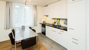 Eine moderne Küche mit weißen Schränken, einer Granitabdeckung und einem Essbereich mit Tisch und Stühlen.