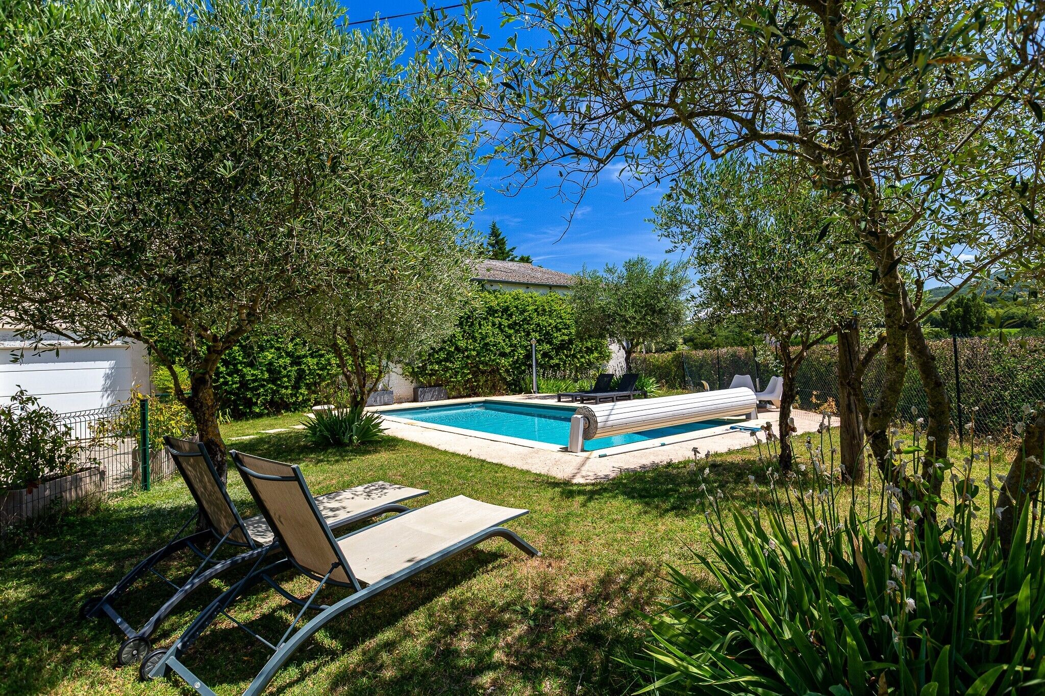 A swimming pool with lounge chairs, surrounded by trees and greenery.