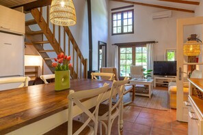 A dining area with a wooden table, white chairs, and a vase of flowers. - Apartment "Gîte La Freydière" Surrounded by Nature in Drôme Provençale (La Bégude-de-Mazenc)