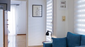 Een woonkamer met een blauwe bank, een lamp en een ingelijst schilderij aan de muur.