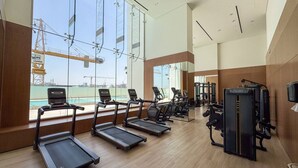 Une salle de sport équipée de tapis de course, de vélos d’exercice et d’appareils de musculation.