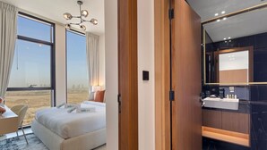 Une chambre d’hôtel moderne, dotée d’un grand lit, d’un bureau et d’une salle de bain avec un grand miroir et un comptoir en marbre noir.