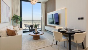 Une chambre d’hôtel moderne dotée d’une grande télévision, d’un coin repas et d’un balcon avec vue.