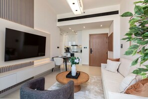 Ein modernes Wohnzimmer mit Flachbildfernseher, Couchtisch, Sofa und Essbereich.