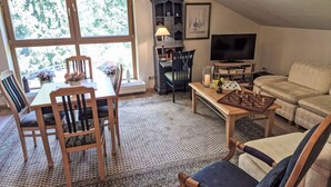 Ein gemütliches Wohnzimmer mit Essbereich, einem Fernseher und einem Schachbrett.