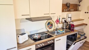 Eine kompakte Küchenzeile mit Herd, Toaster, Spüle und Geschirrspüler.