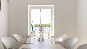 Un espace repas comprenant une table, des chaises et donnant sur un lac.