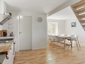 A modern kitchen with a wooden countertop, a sink, and a dining area with white chairs and a table. - Vacation home Rönnö by Interhome (Tingsryd)