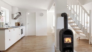 Une cuisine moderne avec des meubles blancs, un plancher en bois, une cuisinière intégrée et un escalier avec des rampes blanches.