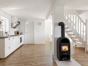 A modern kitchen with white cabinets, a wooden floor, and a wood-burning stove. - Vacation home Rönnö by Interhome (Tingsryd)
