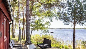 Une cabane dotée d’un espace extérieur aménagé, offrant une vue sur un lac et entourée d’arbres.