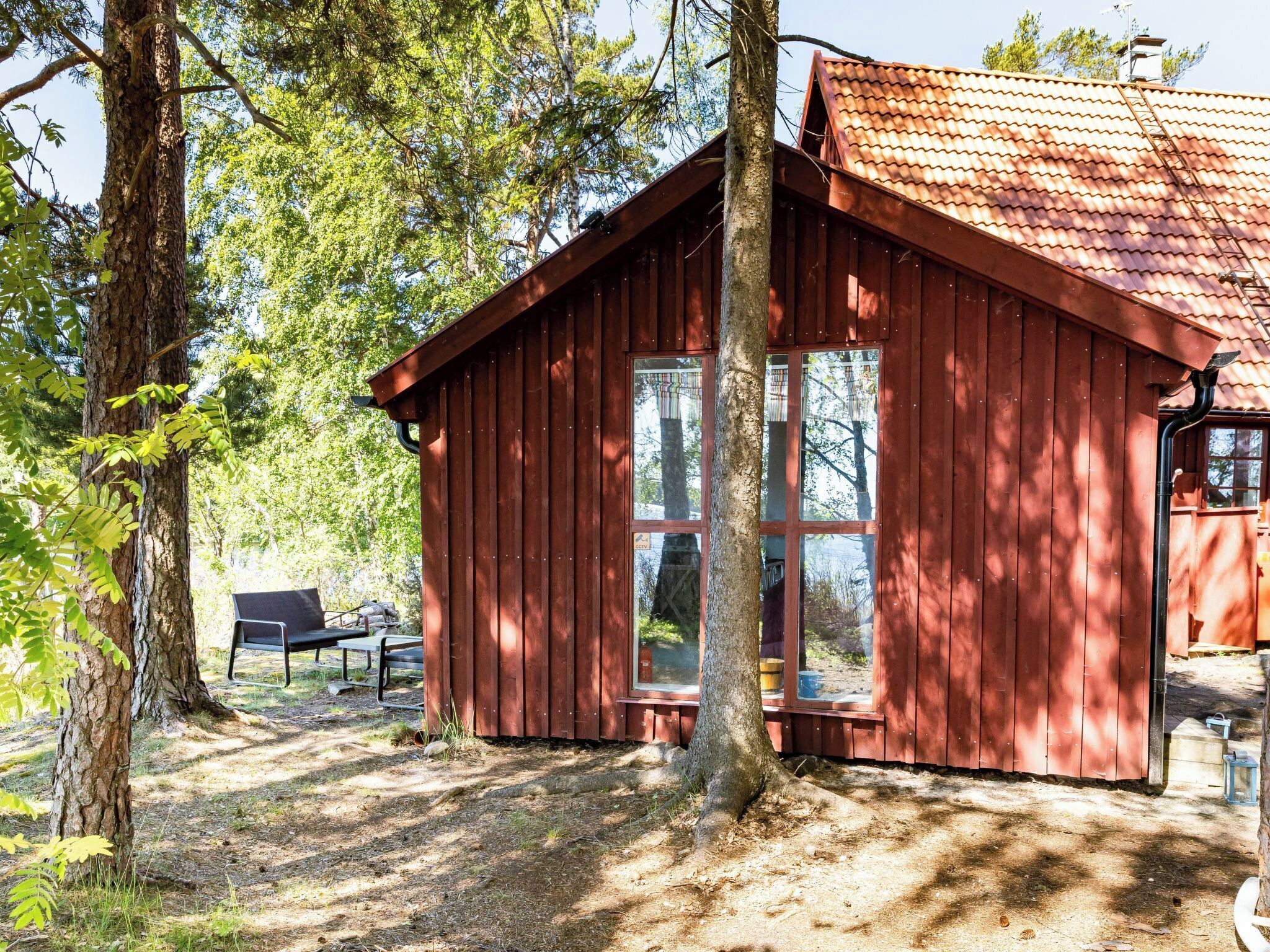 A wooden cabin with a sloped roof, large windows, and a bench outside.