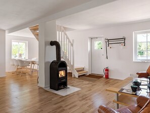 A modern interior with a wood-burning stove, a dining area, and a staircase. - Vacation home Rönnö by Interhome (Tingsryd)