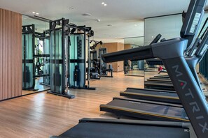 A gym with treadmills, weight machines, and a mirrored wall. - Stylish 1 Bedroom in Binghatti Lavender JVC (Dubai)