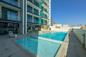 A rooftop pool with clear blue water, surrounded by modern buildings and a clear sky. - Stylish 1 Bedroom in Binghatti Lavender JVC (Dubai)