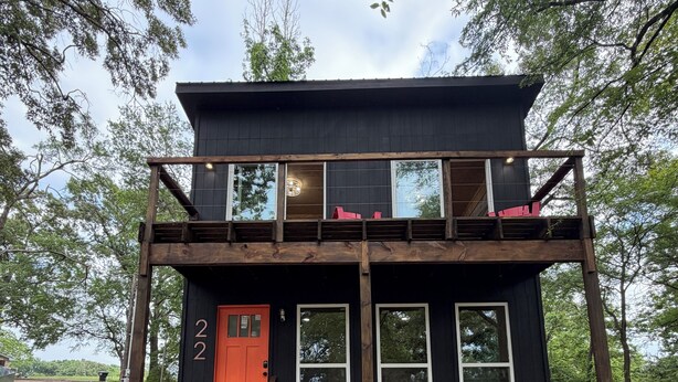 Une cabane à deux étages avec une porte rouge, portant le numéro « 2 », et un petit porche.