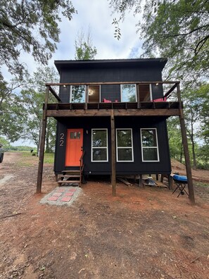 A two-story cabin with a red door, numbered '2', and a small porch. - Lake Fork Water Front Peaceful 2-bedroom cabin-Boat Ramp/Dock (Alba)