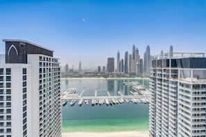 A high-rise building with a marina in the foreground and a city skyline in the background. - Beachfront Bliss 2Bedroom in Grand Bleu (Emaar Beachfront)