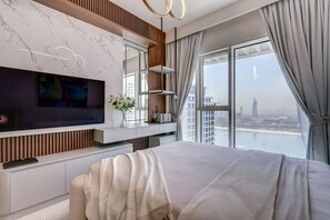 A modern bedroom with a large bed, a TV, and a city view. - Beachfront Bliss 2Bedroom in Grand Bleu (Emaar Beachfront)