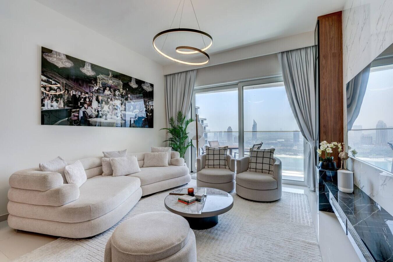 A modern living room with a sectional sofa, two armchairs, a coffee table, and a large window with a city view.