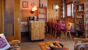 Una cocina compacta con microondas, armarios de madera y una zona de comedor con una mesa dispuesta para cuatro.