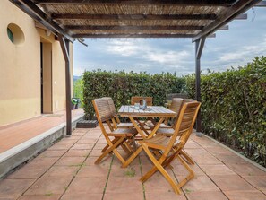 An outdoor patio with a wooden table and chairs, a pergola, and a hedge in the background. - I Quadri by Interhome (Casale Marittimo)