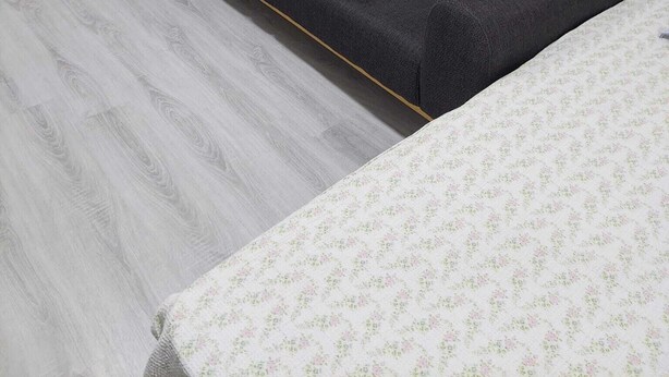 A room with a dark grey sofa, a small white table with a black object on it, and a white radiator. - Alaçatı Evi (Cesme)