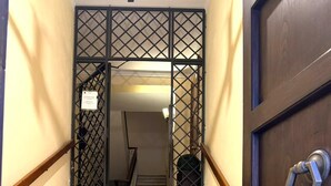A staircase leading to a room with a dark wooden door and a metal gate. - Ninfa Maison Rome | Piazza Navona - Coronari (Roma)