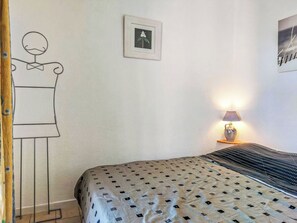Ein Schlafzimmer mit einem Bett, einer Wandlampe, einem gerahmten Bild und einer Wanddekoration.