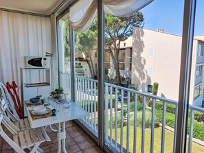 Un balcon équipé d’une table, de chaises, d’un four à micro-ondes et offrant une vue sur un quartier résidentiel.