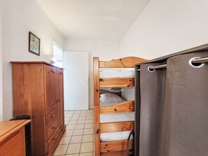 A bedroom with a wooden bunk bed, a wooden dresser, and a door leading to another room. - Le Grand Large by Interhome (Six Fours La Coudoulière)