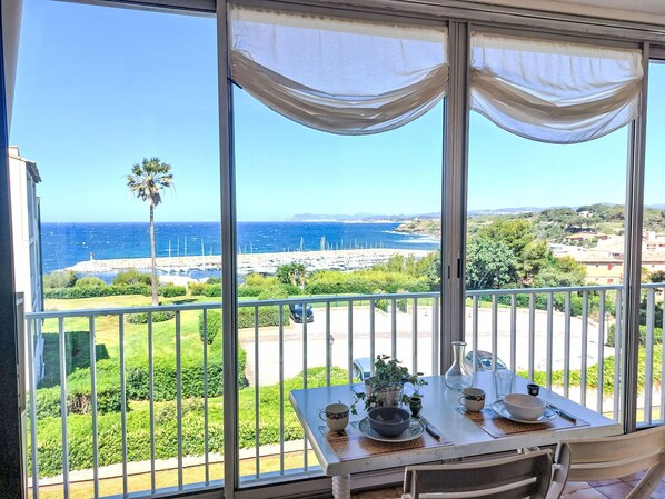 Un balcon avec une table dressée pour le dîner, offrant une vue sur la côte et un ciel dégagé.