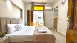 A bedroom with a bed, a window, a door, and a balcony. - La Bella Casa hostel (Cairo)