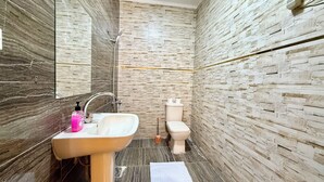 Un baño con lavamanos de mármol, inodoro y ducha.