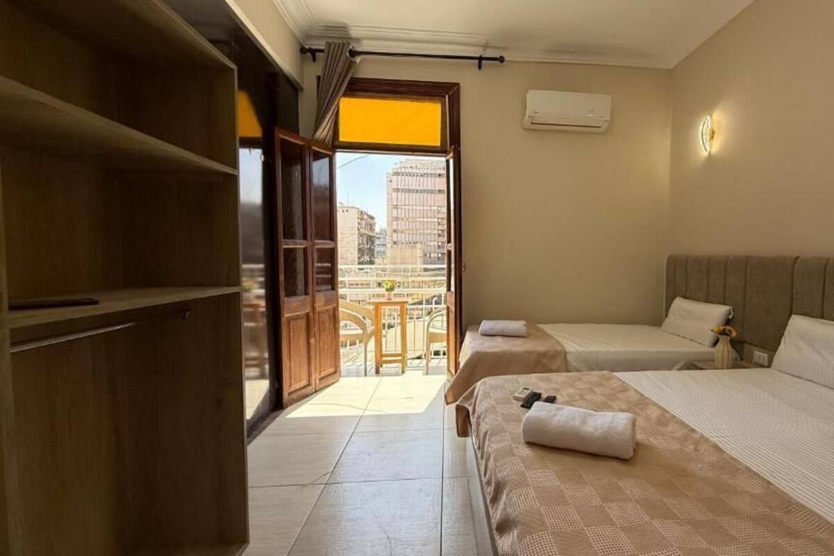 Ein Hotelzimmer mit zwei Betten, einem Balkon, einem Holzschrank und Blick auf die Stadt.