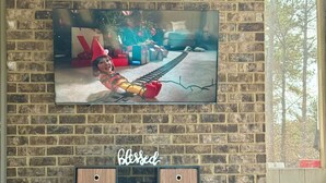 A brick wall with a television mounted above a wooden cabinet with a 'blessed' sign. - World Cup Ready Spacious 5BR Home Near Atlanta Stadium & Downtown Restaurants (Fairburn)
