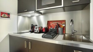A modern kitchen with stainless steel appliances, a toaster, a kettle, and a sink. - Charming Studio With AC Beaubourg Le Marais (Paris)