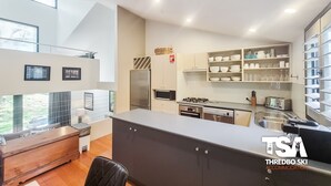 Eine moderne Küche mit Einbauherd, Mikrowelle und Kühlschrank. Es gibt einen Essbereich mit Holztisch und Stühlen.