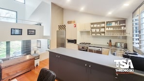 Eine moderne Küche mit Einbauherd, Mikrowelle und Kühlschrank. Es gibt einen Essbereich mit Holztisch und Stühlen.