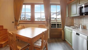 Eine Küche mit Holzausbau, einem Esstisch, Stühlen und Blick auf eine verschneite Landschaft durch ein Fenster.
