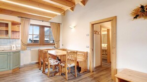 Une table à manger en bois avec des chaises, un coin cuisine avec une fenêtre et un banc en bois.