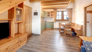 Un intérieur en bois comprenant un téléviseur, des placards, un coin repas et une cuisine.