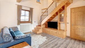 Un intérieur en bois comprenant un canapé, un téléviseur, un escalier et une porte.