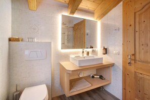 Une salle de bain moderne avec un meuble-lavabo en bois, un grand miroir et des toilettes.
