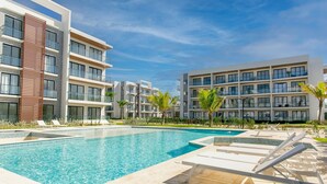 A modern hotel with a swimming pool, multiple balconies, and a well-maintained garden. - Pool View, Gym, and Artificial Beach (Punta Cana)